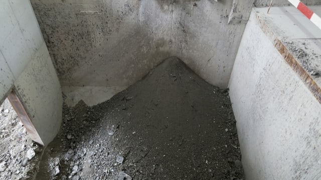 Ascheähnliches Material - schwarz - in einem Bunker aus Beton Ascheähnliches Material - schwarz - in einem Bunker aus Beton