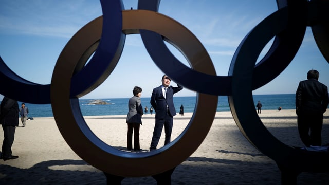 Mann schaut durch Olympiaringe Mann schaut durch Olympiaringe
