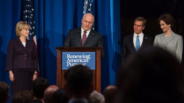 Dick Cheney (Christian Bale) am Rednerpult, George W. Bush (Sam Rockwell) steht daneben und lauscht. Dick Cheney (Christian Bale) am Rednerpult, George W. Bush (Sam Rockwell) steht daneben und lauscht.