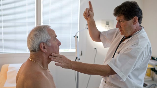Ein Arzt prüft bei einem Patient, ob dieser mit den Augen seinem Finger folgen kann.