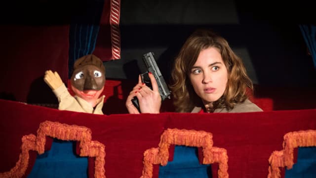 Frau mit Pistole und Gangster-Handpuppe in einem Puppentheater Frau mit Pistole und Gangster-Handpuppe in einem Puppentheater