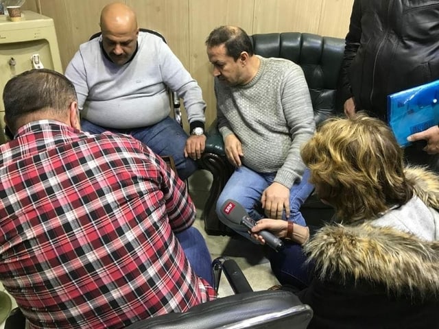 Zwei Männer spielen im Vorzimmer einer Wechselstube Backgammon, vier andere schauen zu. Zwei Männer spielen im Vorzimmer einer Wechselstube Backgammon, vier andere schauen zu.