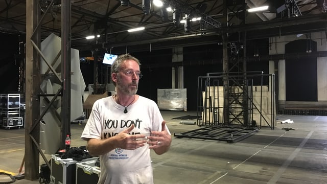 Ein Mann steht in einer leeren Industriehalle. Ein Mann steht in einer leeren Industriehalle.