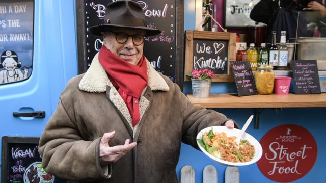 ein Mann mit Hut hält ein Teller mit asiatischem Essen ein Mann mit Hut hält ein Teller mit asiatischem Essen