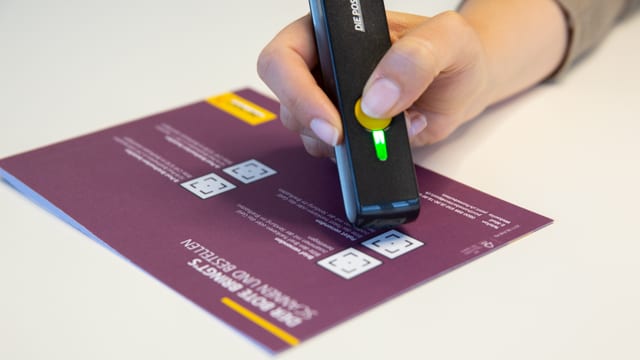Hand hält stiftähnliches Gerät mit gelbem Knopf. Hand hält stiftähnliches Gerät mit gelbem Knopf.