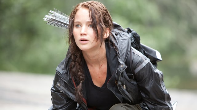 Jennifer Lawrence in «The Hunger Games», knieend mit Pfeil und Bogen
