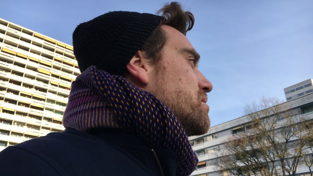 Aron Nick trägt eine Wollmütze und schaut auf die Blöcke im Tscharnergut. Aron Nick trägt eine Wollmütze und schaut auf die Blöcke im Tscharnergut.
