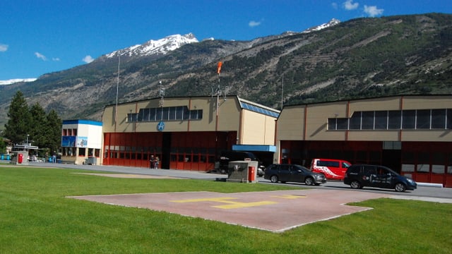 Im Vordergrund Helikopter-Hangars, im Hintergrund Berge. Im Vordergrund Helikopter-Hangars, im Hintergrund Berge.
