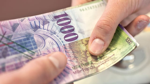 Eine Hand hält eine Tausendernote. Eine Hand hält eine Tausendernote.