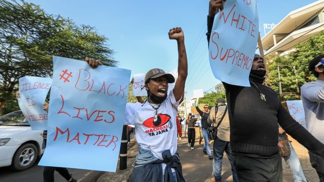 Protestierende mit Plakaten, auf denen steht: Black Lives Matter.
