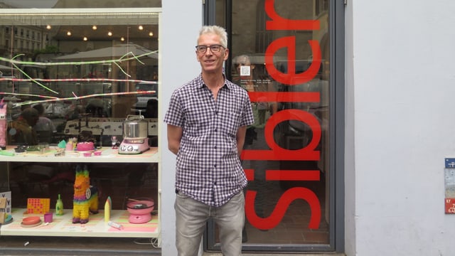 Ein Mann steht vor dem Eingang seines Geschäfts Ein Mann steht vor dem Eingang seines Geschäfts