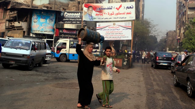 Eine Frau und ein Junge überqueren eine Strasse in Kairo. Eine Frau und ein Junge überqueren eine Strasse in Kairo.