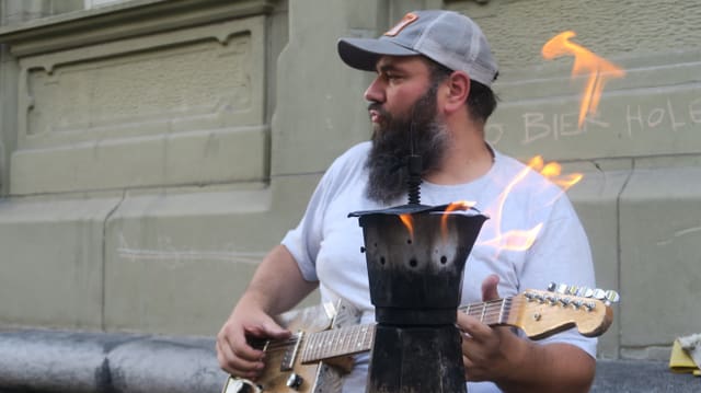 Ein Mann mit Käppi spielt Gitarre. Ein Mann mit Käppi spielt Gitarre.