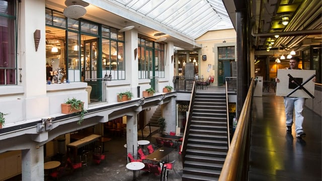 Mann trägt Tisch durch die Markhalle Mann trägt Tisch durch die Markhalle