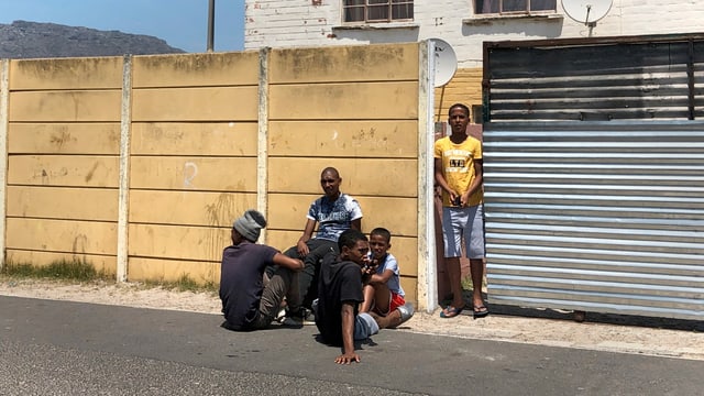 Eine Gruppe Männer sitzt vor Wand Eine Gruppe Männer sitzt vor Wand