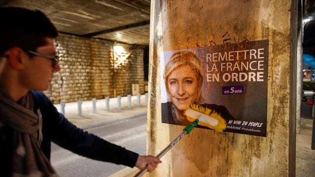 Wahlplakat von Marine Le Pen wird an einer Mauer angebracht. Wahlplakat von Marine Le Pen wird an einer Mauer angebracht.