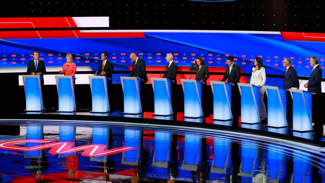 Zehn Präsidentschaftskandidaten der Demokraten stehen an Rednerpulten bei der TV-Debatte. Zehn Präsidentschaftskandidaten der Demokraten stehen an Rednerpulten bei der TV-Debatte.