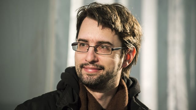 Ein Mann mit dunklen Haaren und Brille schaut in die Kamera. Ein Mann mit dunklen Haaren und Brille schaut in die Kamera.