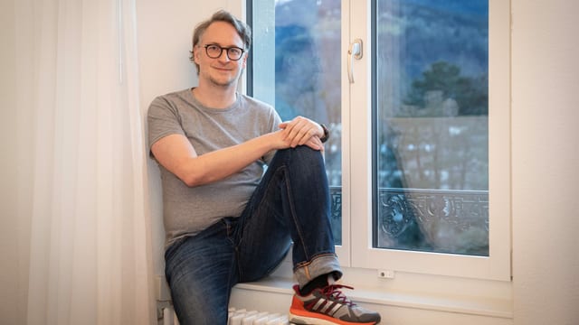 Ein Mann sitzt auf einer Fensterbank. Ein Mann sitzt auf einer Fensterbank.