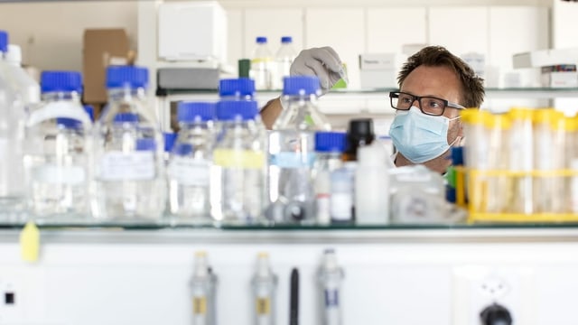 Ein Mann mit Mundschutz steht in einem Labor. Ein Mann mit Mundschutz steht in einem Labor.