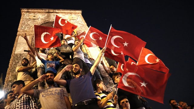Umens e buobs stattan sco en ina sort piramida avant in monument sil la plazza Taksim ad Istanbul. Entgins tegnan lur maun al frunt per il salid militaric. Blers tegnan bandieras tircas. Umens e buobs stattan sco en ina sort piramida avant in monument sil la plazza Taksim ad Istanbul. Entgins tegnan lur maun al frunt per il salid militaric. Blers tegnan bandieras tircas.