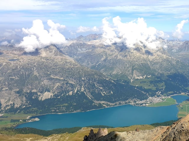 Dr Blick vom Gipfel hinunter ins Tal, dort leuchten die die tükis grünen Engandienerseen in der Sommersonne.