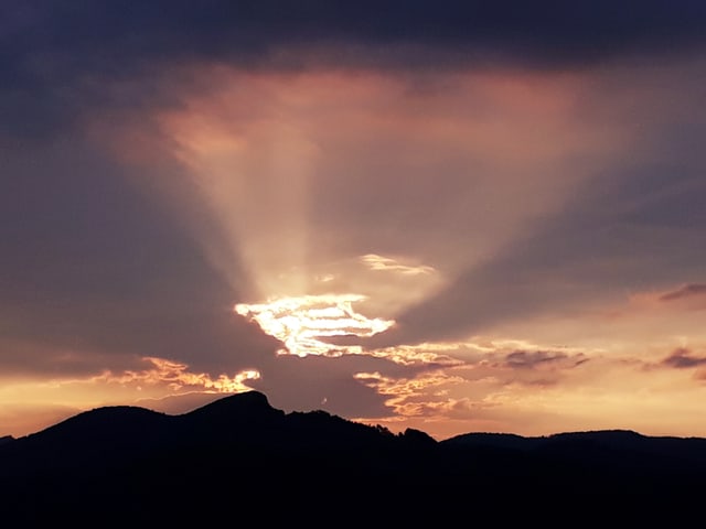 Die Sonne geht hinter Wolken unter.