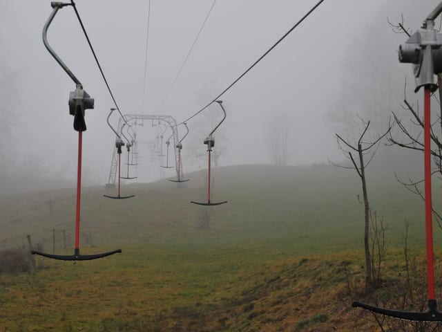 Ein Skilift im Nebel, alles ist nass, aber eben nicht weiss.
