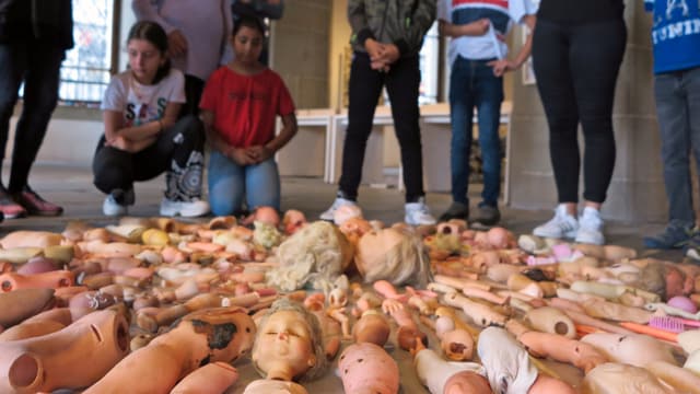 Kunstinstallation aus Abfällen, die am Boden liegen. Kinder betrachten die gesammelten Dinge. Kunstinstallation aus Abfällen, die am Boden liegen. Kinder betrachten die gesammelten Dinge.