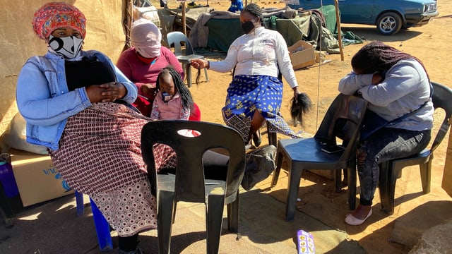 Fünf Frauen sitzen im Kreis an einer Wand in Südafrika. Fünf Frauen sitzen im Kreis an einer Wand in Südafrika.