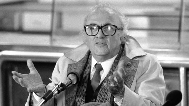 Federico Fellini steht gestikulierend vor einem Mikrofon. Federico Fellini steht gestikulierend vor einem Mikrofon.