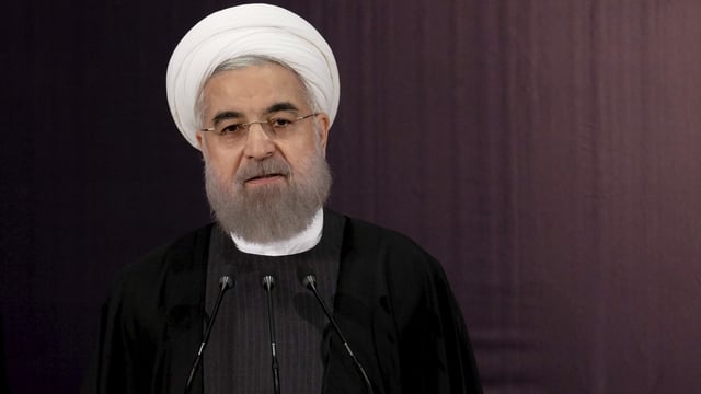 Portrait von Irans Präsident Rohani mit weissem Turban vor dunklem Hintergrund. Er spricht in Mikrofone. Portrait von Irans Präsident Rohani mit weissem Turban vor dunklem Hintergrund. Er spricht in Mikrofone.