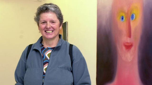 Eine Frau steht in einer Ausstellung vor zwei rosafarbenen Gemälden. Eine Frau steht in einer Ausstellung vor zwei rosafarbenen Gemälden.