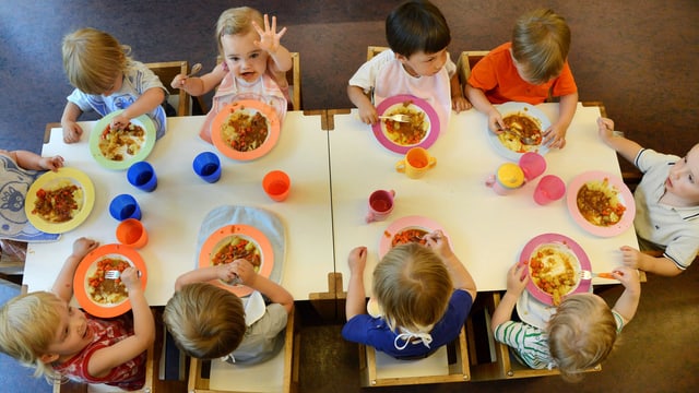 10 Kinder essen an einem Tisch. 10 Kinder essen an einem Tisch.