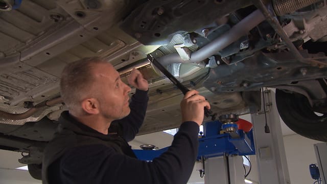 Mann untersucht das Auto von unten - Mann untersucht das Auto von unten -