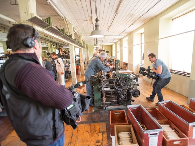 Tontechniker und Kameramann im Bild, filmen Webmeister am Webstuhl in Fabrik