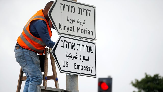 Ein Mann montiert das Strassenschild für die US-Botschaft in Jerusalem. Ein Mann montiert das Strassenschild für die US-Botschaft in Jerusalem.