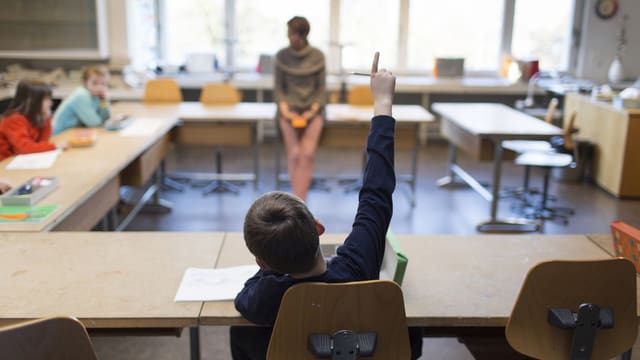Ein Schüler hebt die Hand im Unterricht. Ein Schüler hebt die Hand im Unterricht.