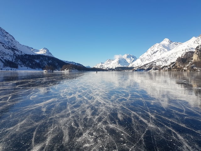Der Silsersee ist zugefroren, der See ist wegen Schwarzeis spiegelglatt.