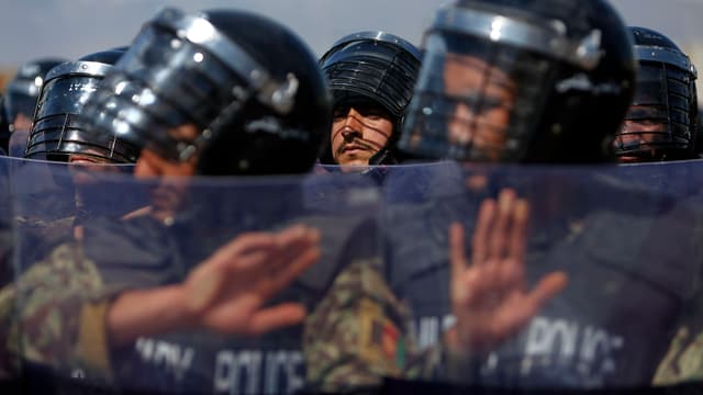 Militärpolizisten stehen in einer Reihe und halten Schilde hoch Militärpolizisten stehen in einer Reihe und halten Schilde hoch