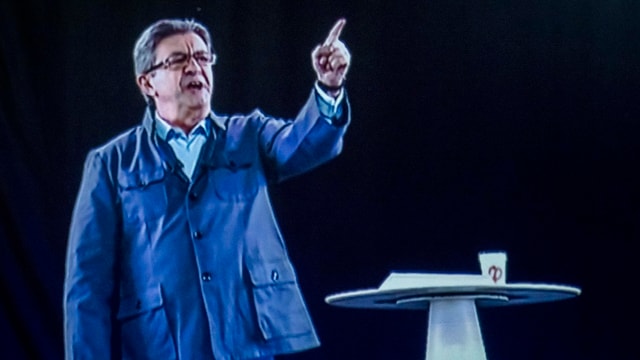 Jean-Luc Mélenchon steht als eine Art Hologram auf der Bühne. Jean-Luc Mélenchon steht als eine Art Hologram auf der Bühne.
