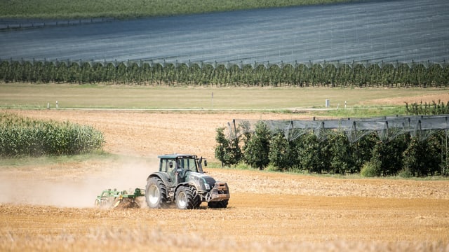 Ein Traktor fährt auf einem Feld. Der Boden ist sehr trocken. Ein Traktor fährt auf einem Feld. Der Boden ist sehr trocken.