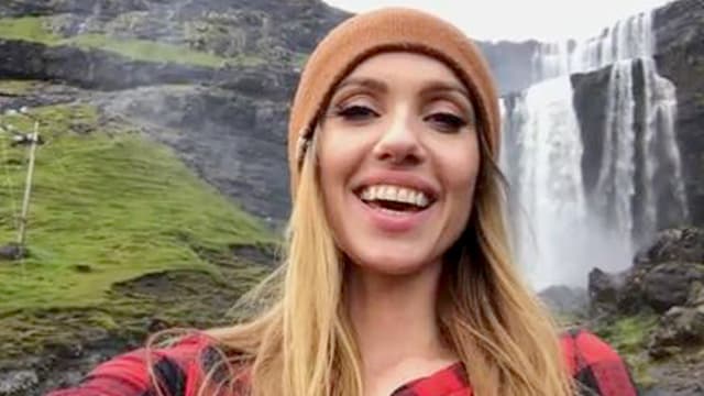 Eine junge Frau steht vor einem Wasserfall. Eine junge Frau steht vor einem Wasserfall.