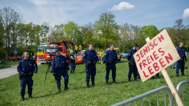 Eine Reihe Polizisten auf einer Wiese, im Vordergrund ein Schild mit roten Lettern: «Jenisch freies Leben» Eine Reihe Polizisten auf einer Wiese, im Vordergrund ein Schild mit roten Lettern: «Jenisch freies Leben»