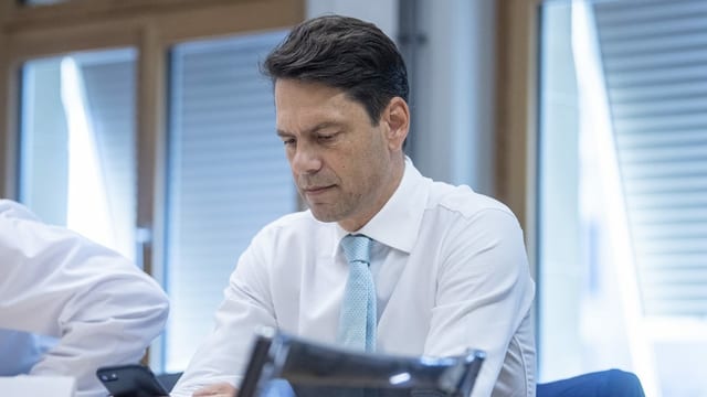 Purtret da Brupbacher che guarda cun ina fatscha pensiva sin ses telefonin. Purtret da Brupbacher che guarda cun ina fatscha pensiva sin ses telefonin.