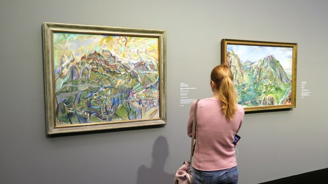 Eine Frau steht vor zwei Landschaftsbildern Eine Frau steht vor zwei Landschaftsbildern