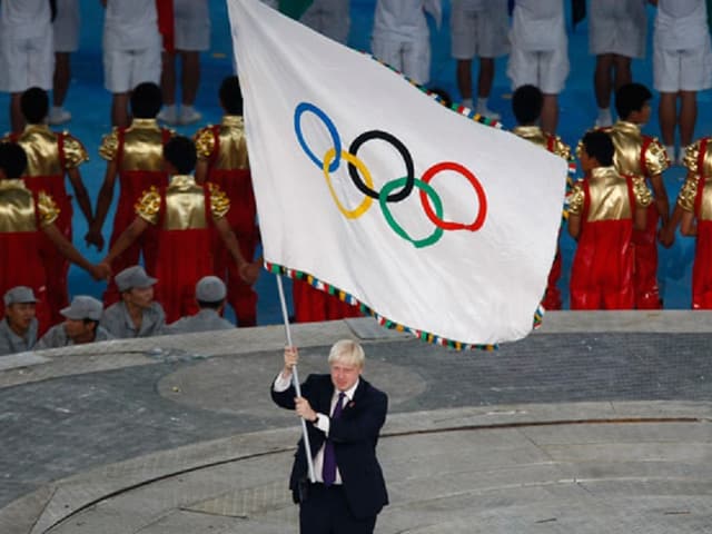 La bandiera olimpica vegn purtada en il stadion. La bandiera olimpica vegn purtada en il stadion.