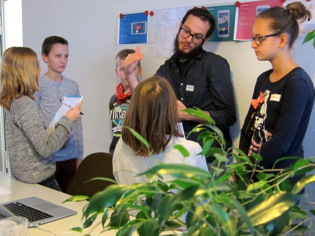 Ein bärtiger Mann redet mit fünf Kindern. Ein bärtiger Mann redet mit fünf Kindern.