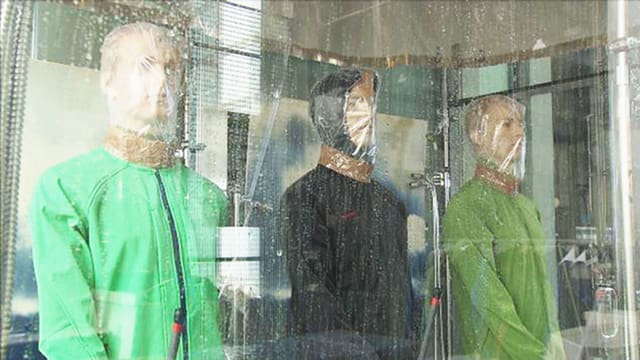 Drei Puppen mit Softshell-Jacken sind künstlichem Regen ausgesetzt. Drei Puppen mit Softshell-Jacken sind künstlichem Regen ausgesetzt.