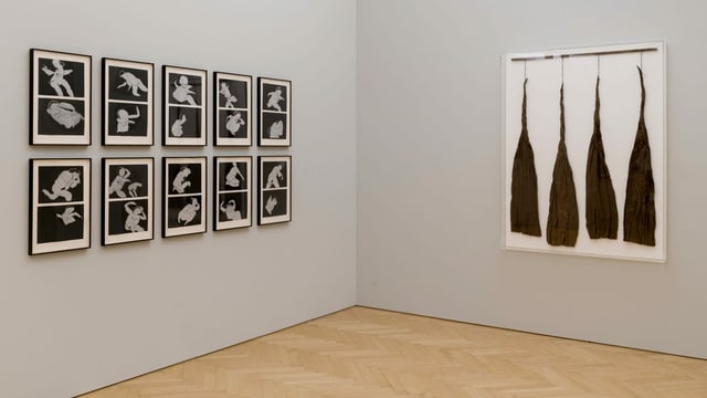 10 Schwarz-Weiss-Bilder mit abstrakten Frauenfiguren hängen an einer grauen Wand. 10 Schwarz-Weiss-Bilder mit abstrakten Frauenfiguren hängen an einer grauen Wand.